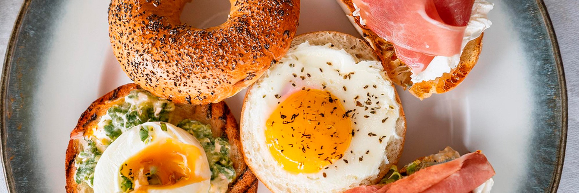 Gourmet breakfast bagel with sausage, fried egg and melted cheese served fresh at Roatan Provision.